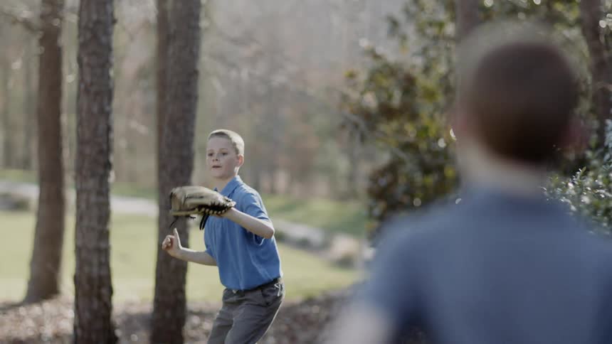 Boys play baseball on a front lawn