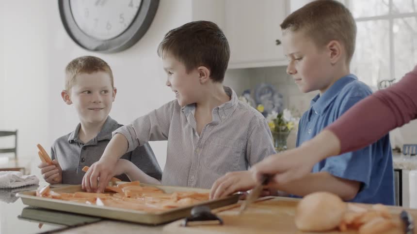 Woman and boys cook potatoes at home