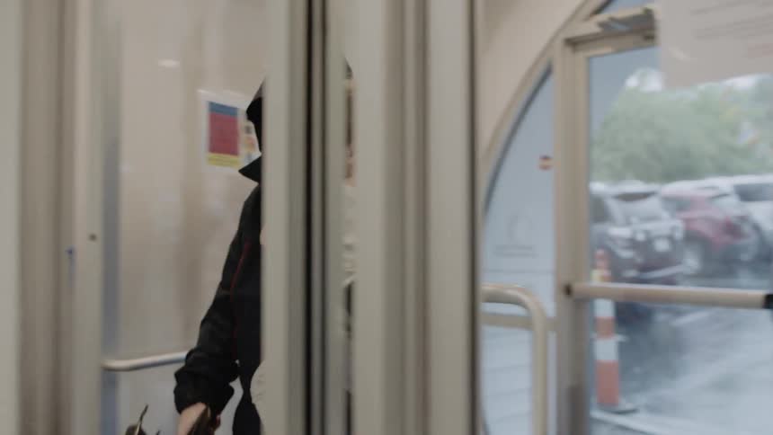 A man enters a building carrying a child and an umbrella