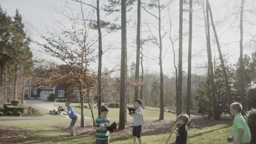 Boys play ball on a front lawn
