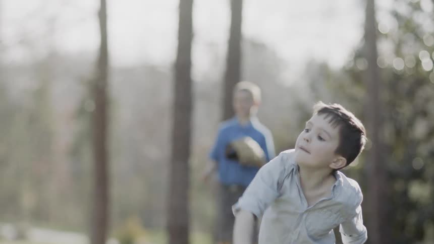 Young boys play ball near the trees