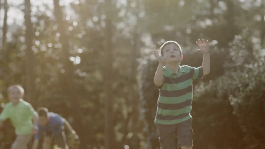 Man plays ball with young boys at sunset
