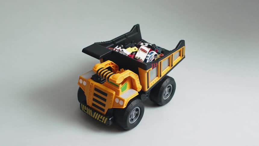 Hot wheels are stacked in the back of a toy dump truck