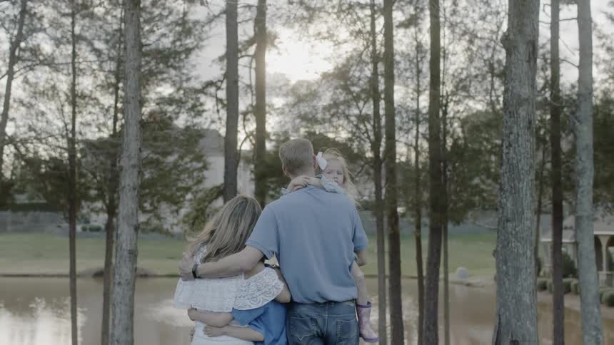 A family hug by the lake on a cloudy day