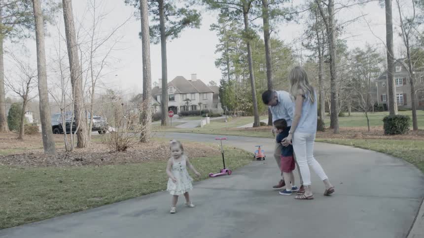 A young family walks on a neighborhood sidewalk
