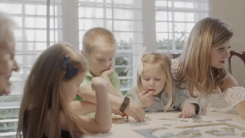 A family does a puzzle at a dining table