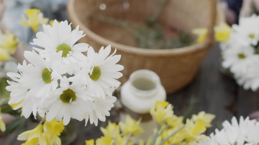Person puts herbs into a basket near a bunch of white flowers