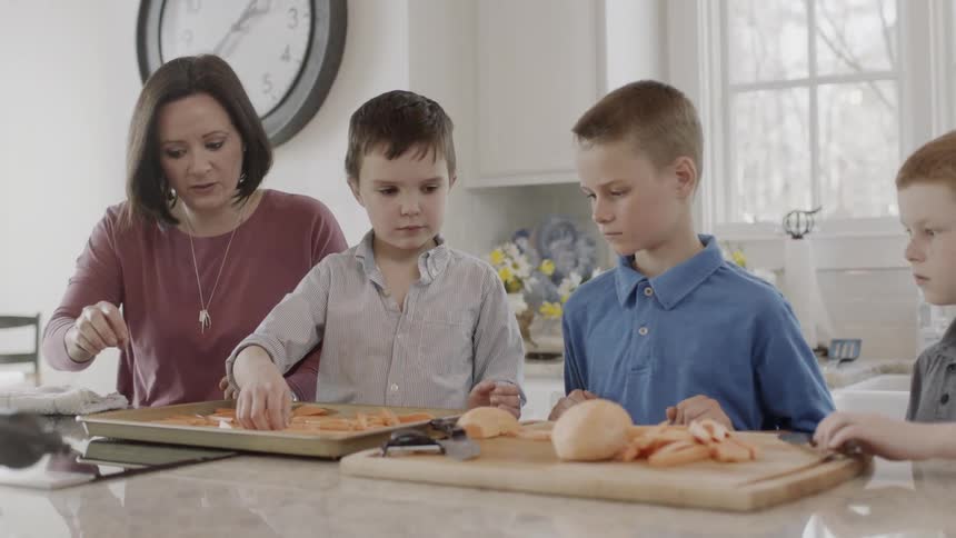 A mom and her three kids are getting vegetables on a tray