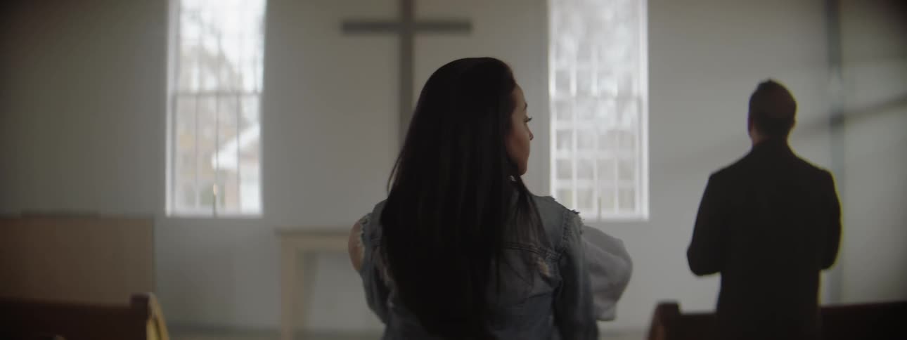Woman carries a baby down an aisle in a church