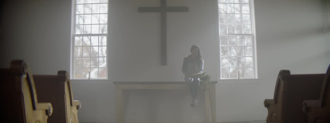 A woman sits on the table by the cross in church