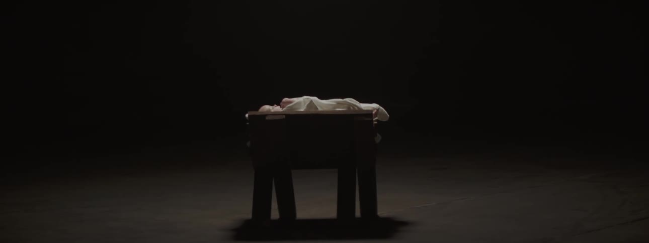 Bay lays on a table waving its arms in an empty room