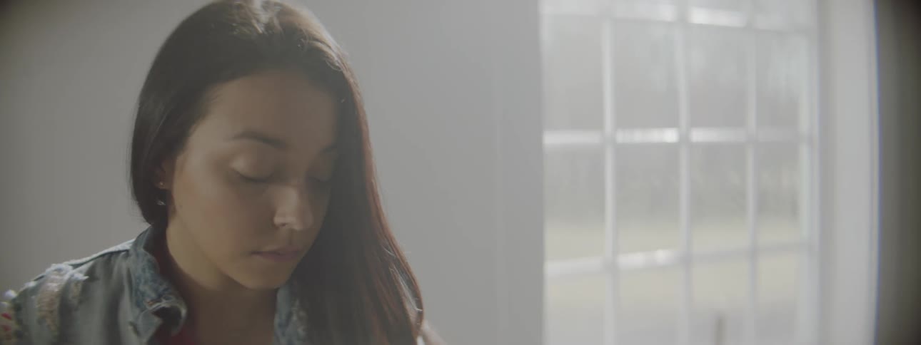 Woman sits near a window illuminated by the sun