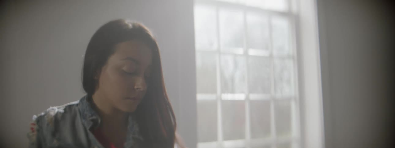 Woman sitting with eyes closed with sun shining in a window