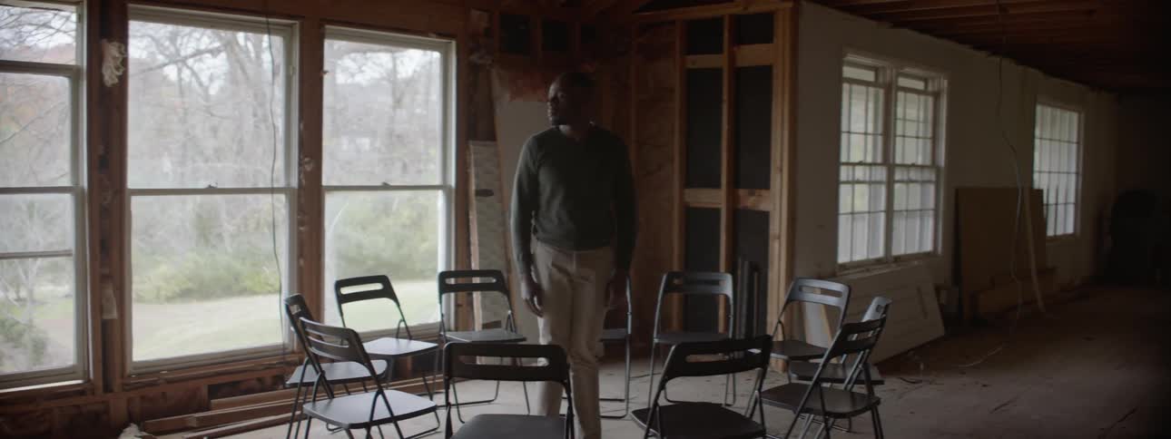 A man stands in the middle of a circle of chairs