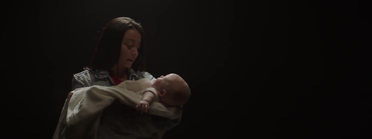 Woman holds a baby in a dim room