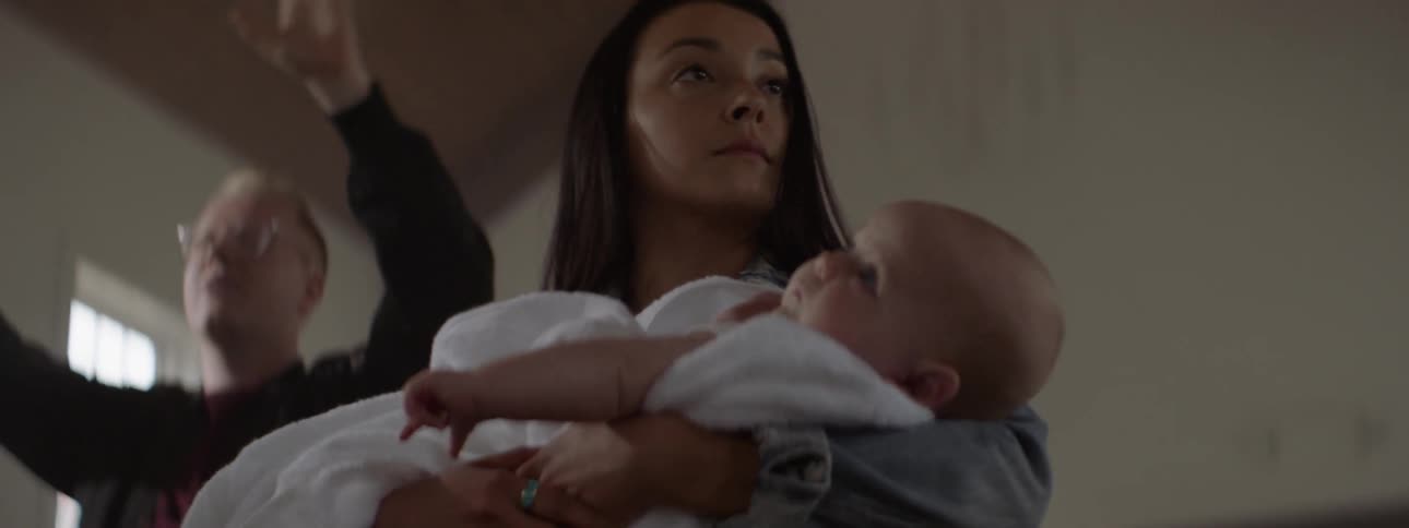 Woman carries a baby walking through a house