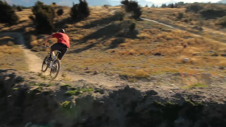 Man rides a bike down a dirt trail on some hills