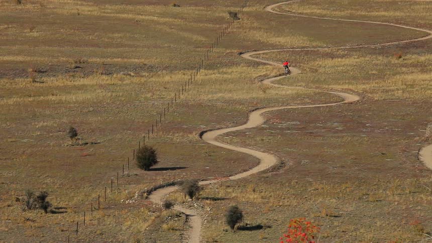 Man riding his bike down a curved trail on a field