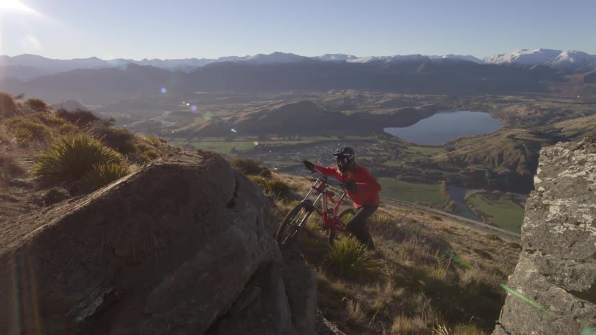 Man pushes his bike up the hill of a mountain on a sunny day