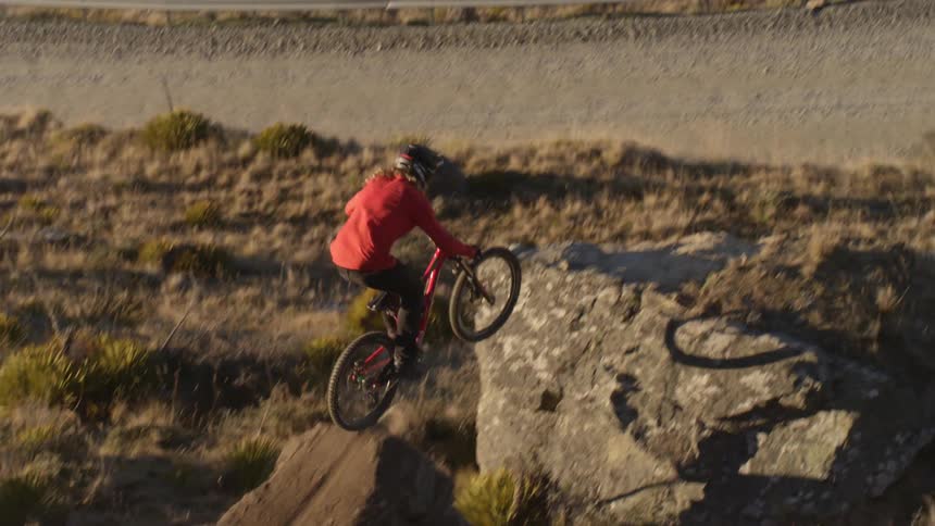 Person riding their bike jumps a huge rock with a ramp