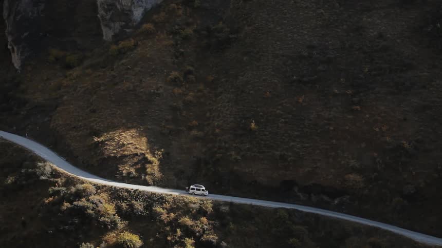 A van travels on a narrow mountain road