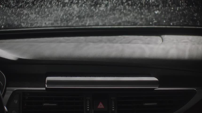 Rain pelts down on a car windshield
