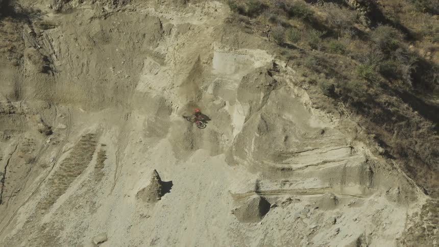 Man falling off his bike rolling down a large dirt hill
