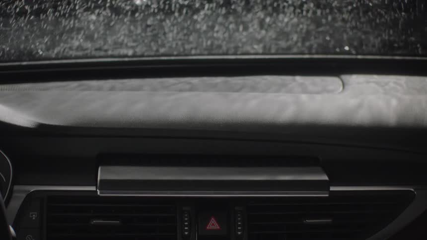Water splashes off the windshield of a car and a monitor pops up inside