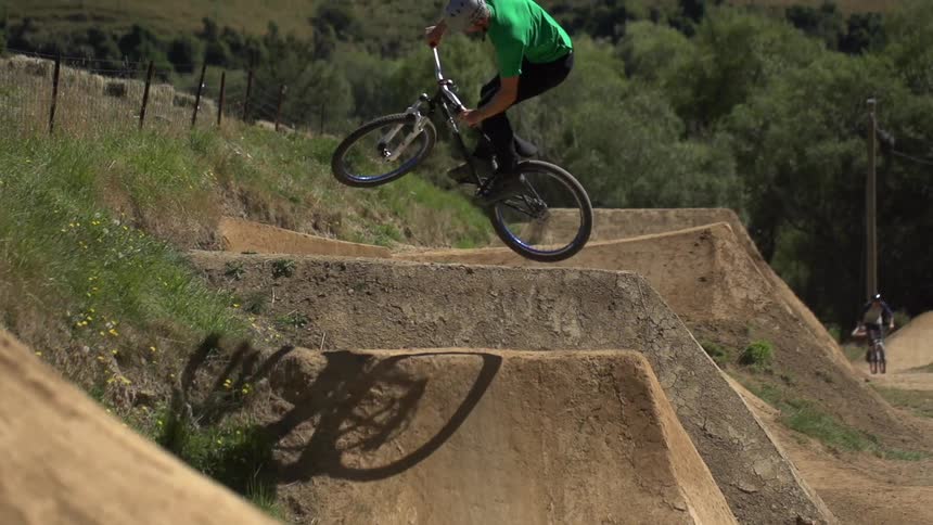 Man riding a bike up and down some dirt hills