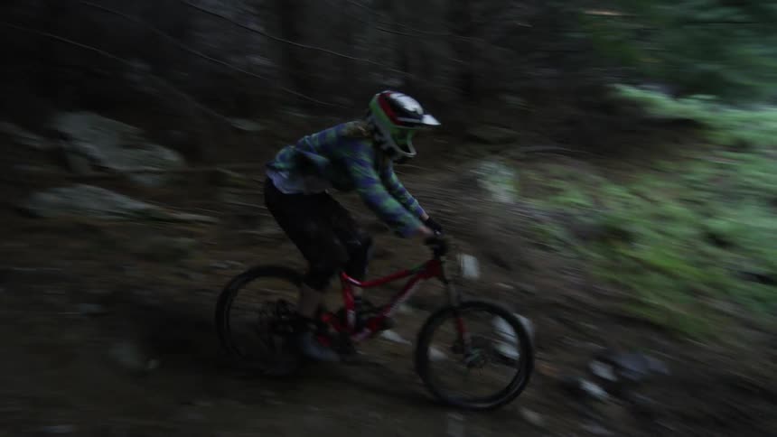 Man riding a bike downhill in a dark forest