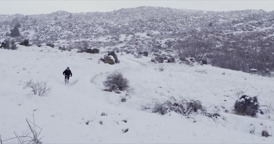 A mountain biker is riding their bike on a snowy trail