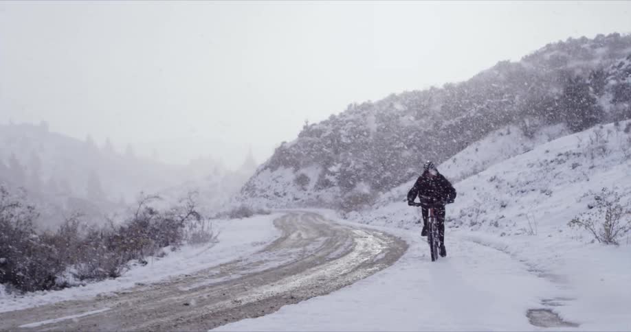 Man riding his bike as it heavily snows