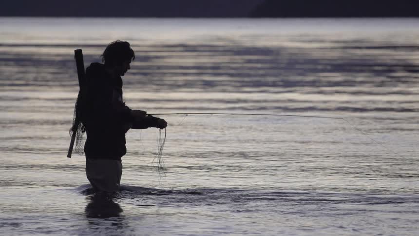 A man wades and fishes in a river