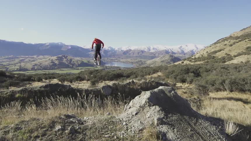 A mountain biker is jumping his bike off a big jump