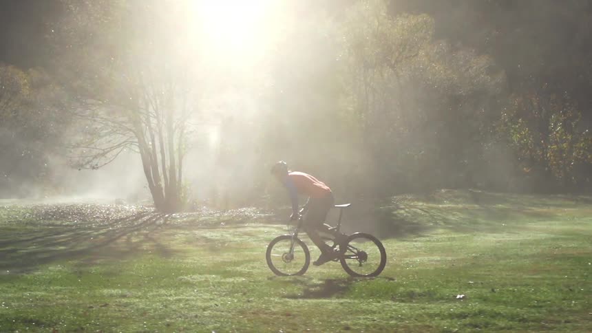 Man riding his bike in the grass on a foggy day