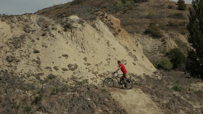 A man walks a bicycle up a hill in the wilderness