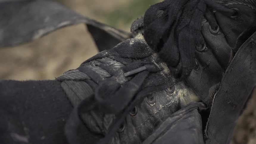 A man is outdoors and tying his shoe