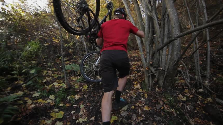 Man carrying his mountain bike up a steep hill