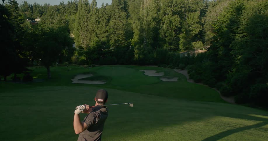 Man swings his golf club and hits the golf ball towards the hole