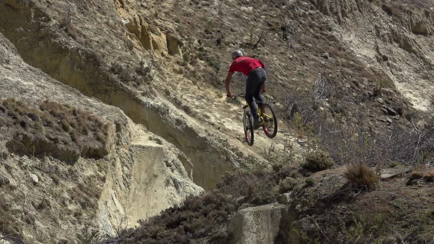 Man riding his bike doing jumps on a hilly mountain