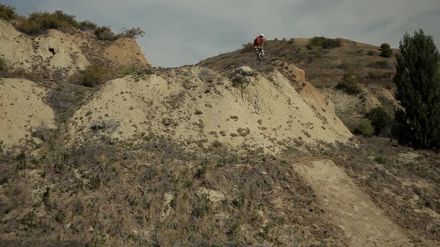 A bicyclist jumps off a large dirt hill
