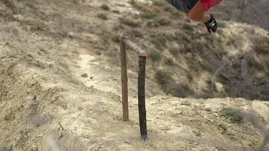 A man riding a bike is doing a trick over a dusty dirt hill