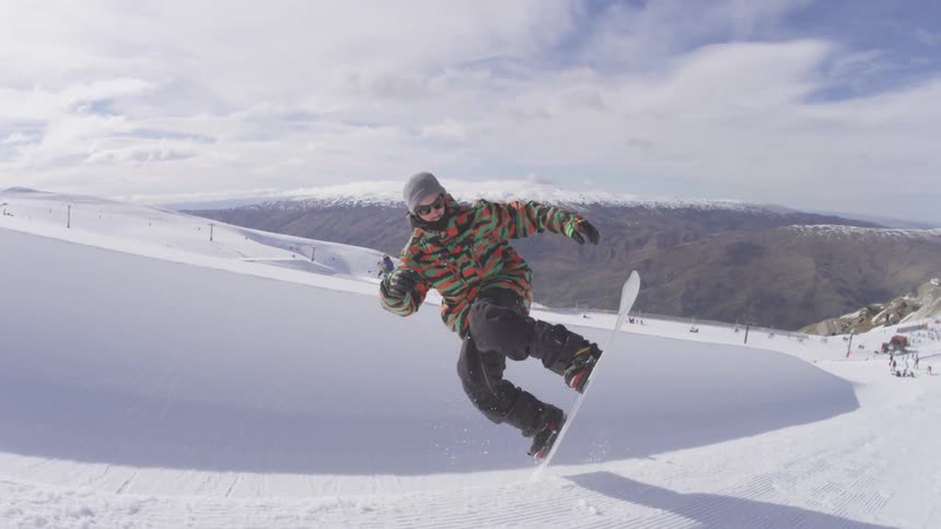 A snowboarder going down one wall of snow, up the other side and jumping in the air before landing