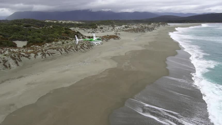 A helicopter is flying over the beach
