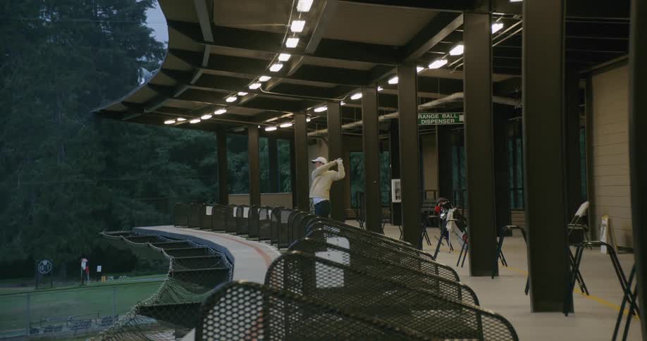 Man hits a golf ball off a building