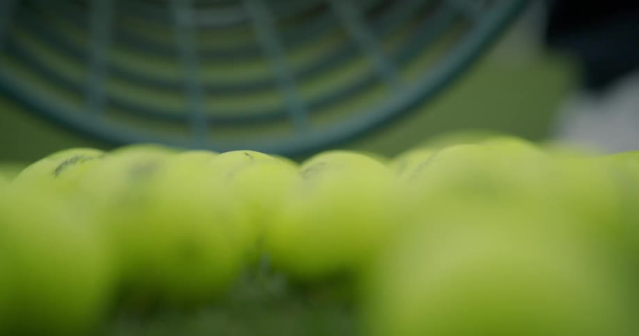 Basket of tennis balls spill and bounce on grass