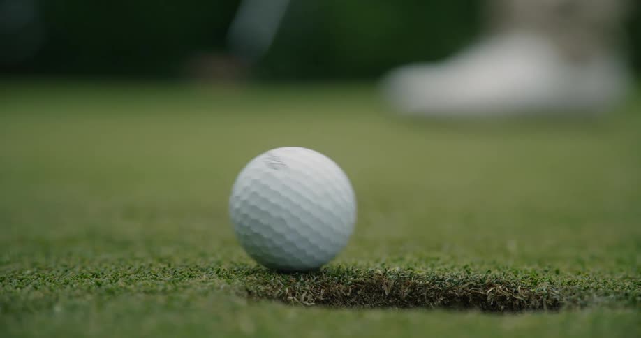 Golf ball rolls on a green into a hole