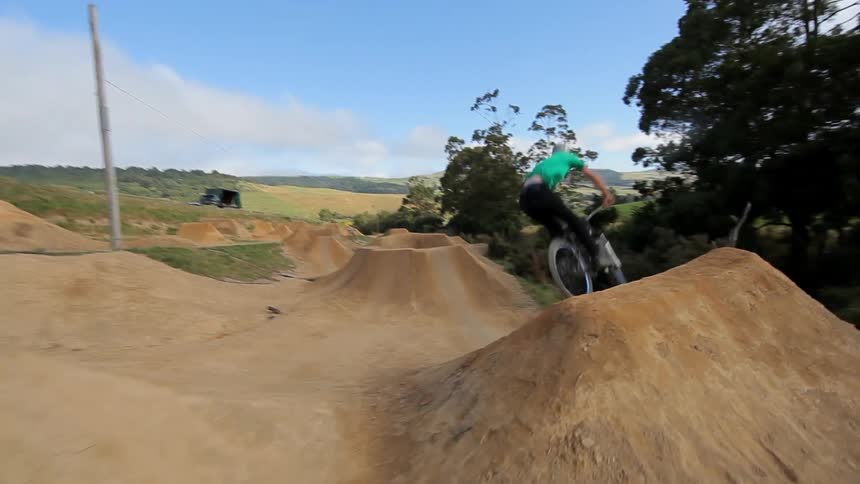 Man riding up hills and doing jumps on a track with his bike