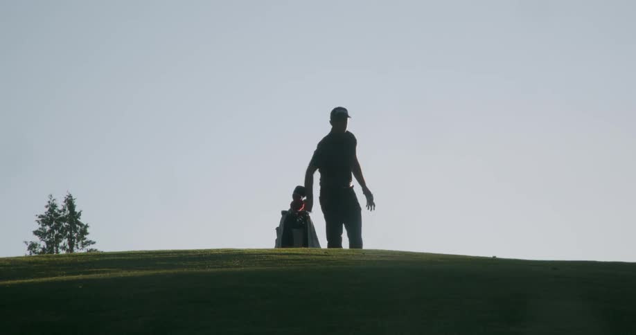 Man carrying bag of golf clubs on a golf green