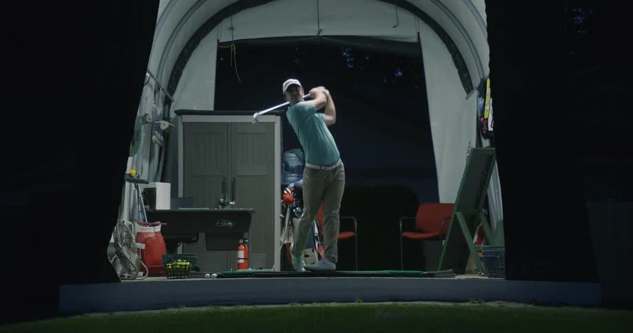 A man practicing his golf swing indoors